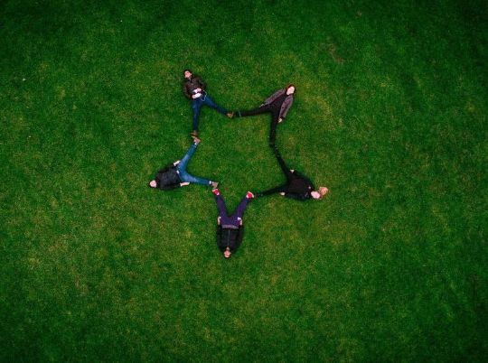 People making a star together on grass